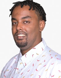 a photo of a person with a goatee smiling and wearing a white and blue pinstripe button-down shirt. 